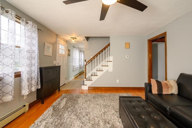 living room with light hardwood / wood-style floors, ceiling fan, and a baseboard heating unit