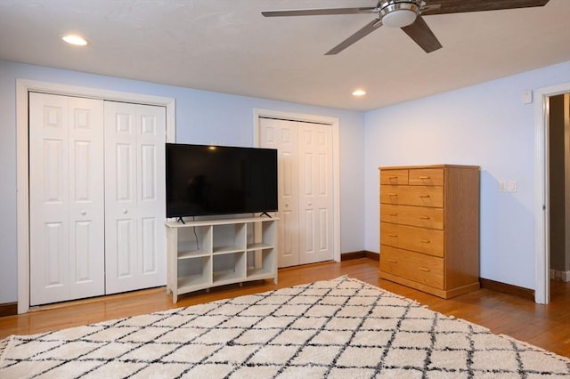 unfurnished bedroom with hardwood / wood-style flooring, ceiling fan, and two closets