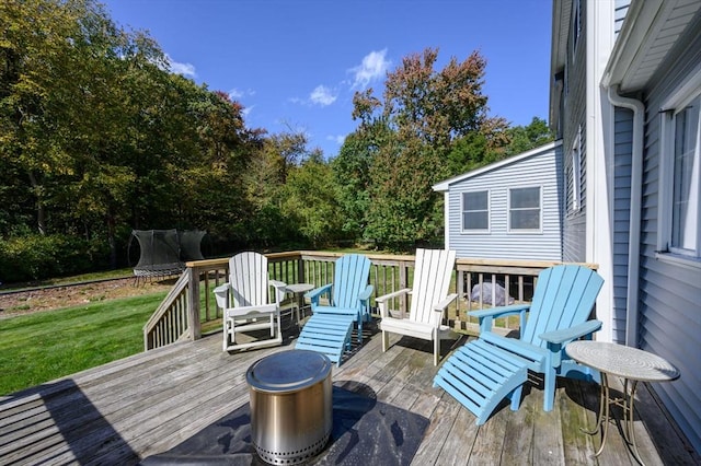 wooden terrace featuring a lawn and a trampoline