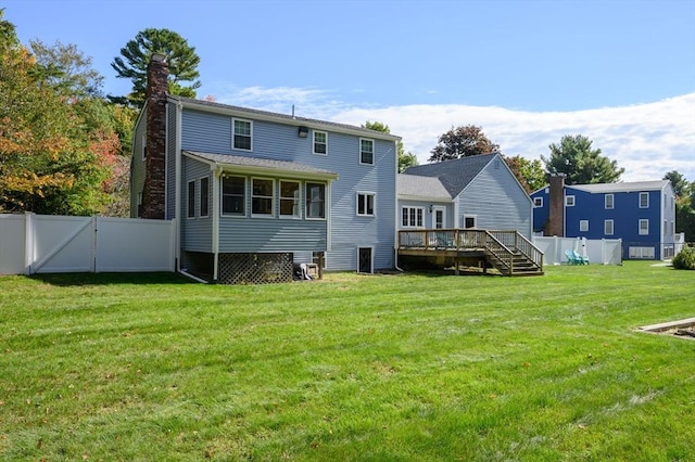 rear view of house featuring a lawn and a deck