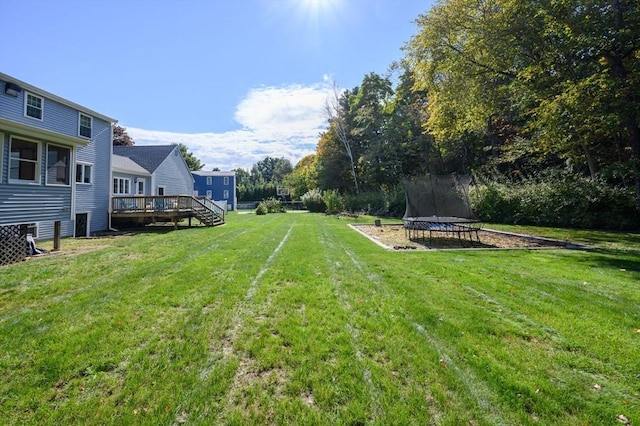 view of yard with a wooden deck and a trampoline