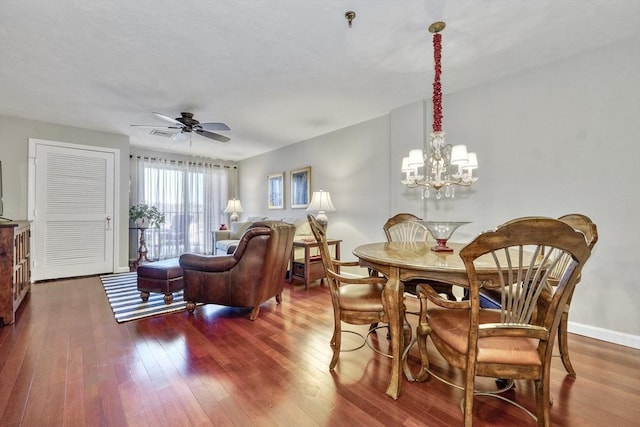 dining area with dark wood-type flooring and ceiling fan with notable chandelier