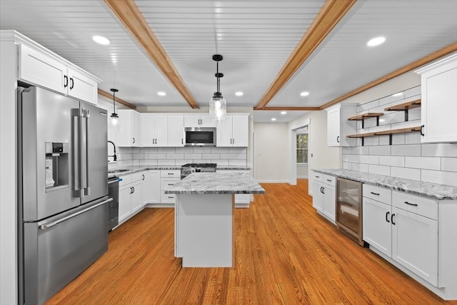 kitchen with light wood-type flooring, wine cooler, decorative light fixtures, white cabinets, and appliances with stainless steel finishes