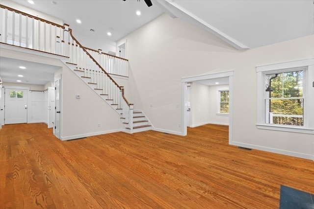 unfurnished living room with ceiling fan, light hardwood / wood-style floors, and high vaulted ceiling