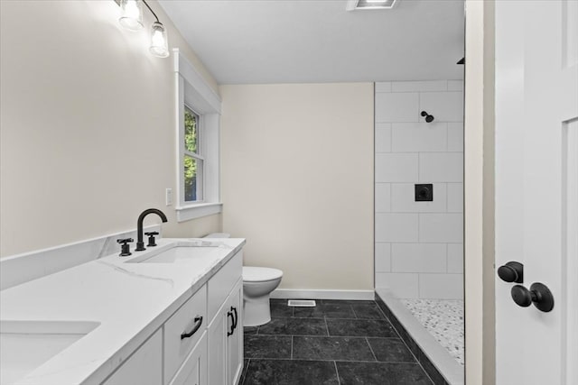 bathroom featuring a tile shower, vanity, toilet, and tile patterned floors