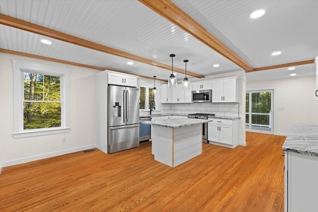 kitchen with light wood-type flooring, stainless steel appliances, white cabinets, sink, and pendant lighting