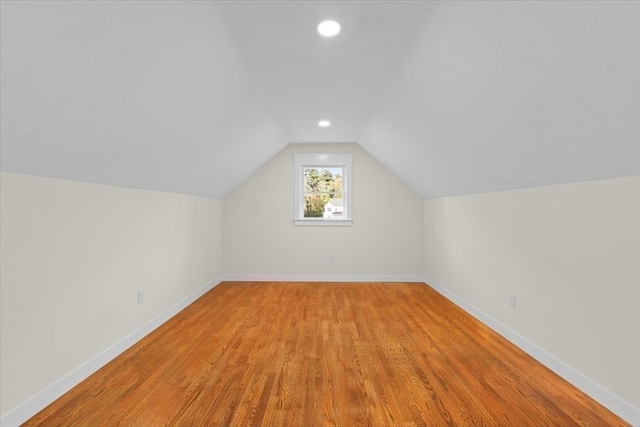 additional living space featuring vaulted ceiling and light hardwood / wood-style floors