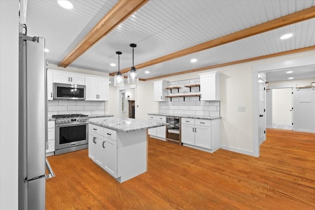 kitchen with white cabinets, appliances with stainless steel finishes, a barn door, and a kitchen island