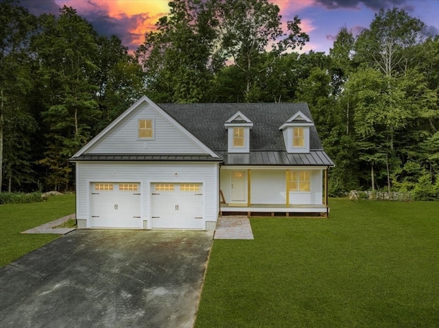 view of front of property featuring covered porch, a lawn, and a garage