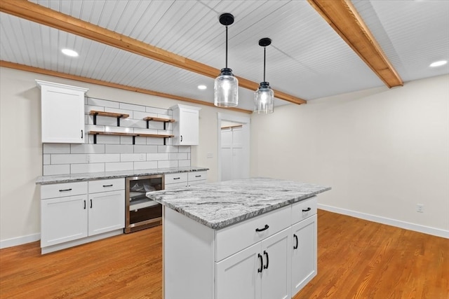 kitchen with beverage cooler, light hardwood / wood-style floors, white cabinetry, decorative light fixtures, and backsplash