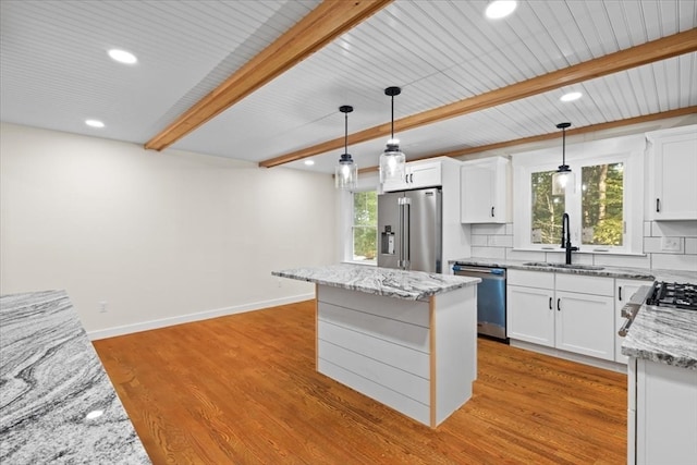 kitchen with appliances with stainless steel finishes, a center island, sink, and white cabinetry