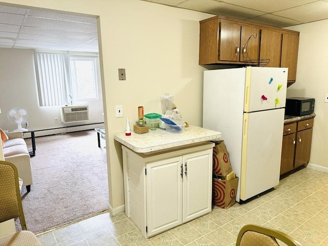 kitchen with a wall unit AC, a paneled ceiling, white fridge, and baseboard heating