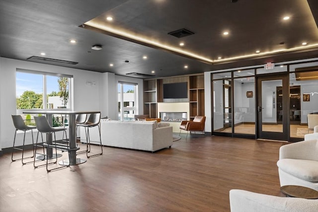 living room featuring visible vents, recessed lighting, a tray ceiling, and wood finished floors