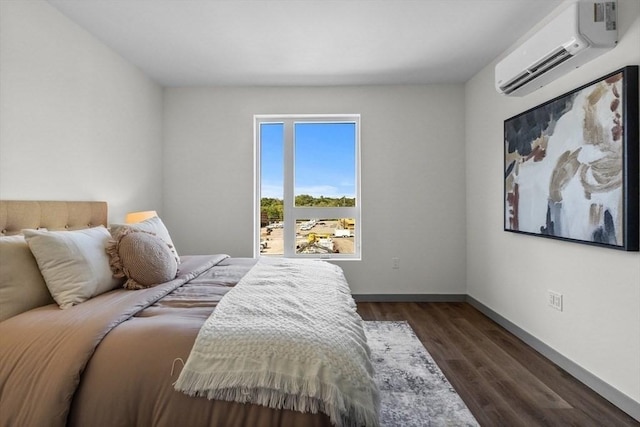 bedroom with dark wood-style floors, baseboards, and a wall mounted air conditioner