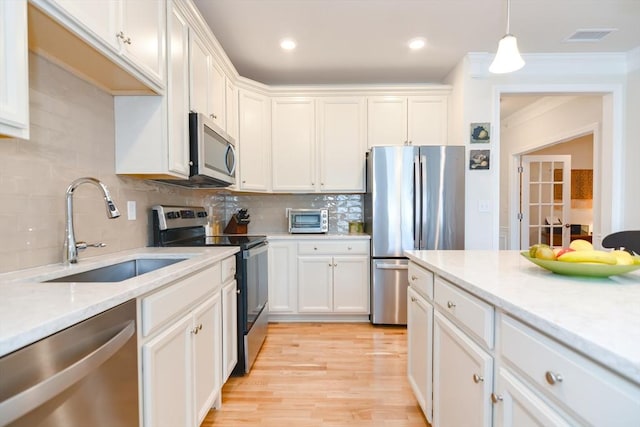 kitchen with white cabinets, appliances with stainless steel finishes, light wood-style flooring, and a sink