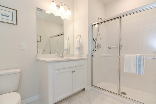 bathroom with vanity, toilet, baseboards, and a stall shower