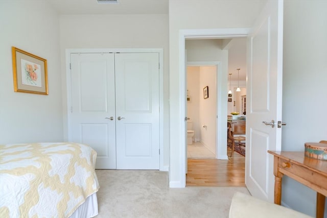 bedroom with visible vents, light colored carpet, and a closet