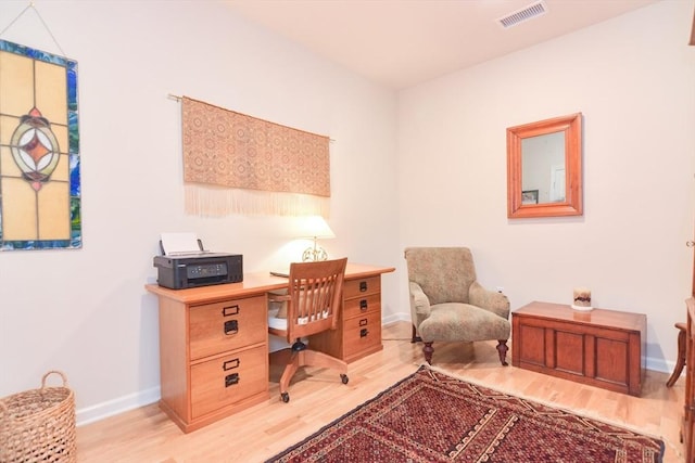 home office with light wood-style flooring, baseboards, and visible vents