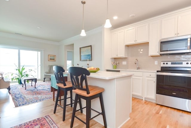 kitchen featuring a sink, light countertops, appliances with stainless steel finishes, light wood-type flooring, and backsplash