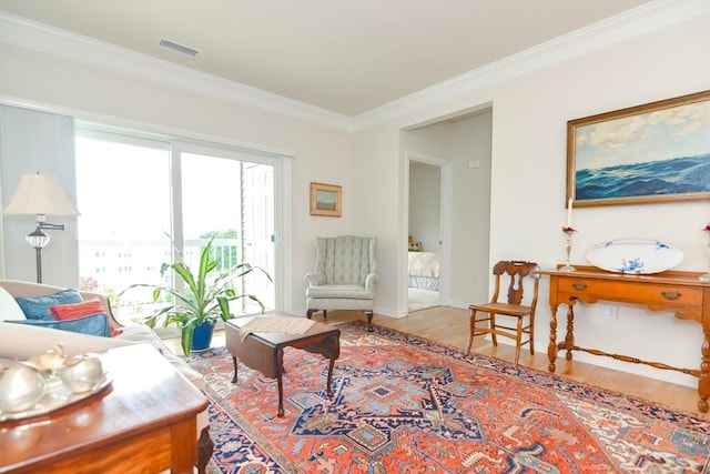 living area with visible vents, baseboards, wood finished floors, and ornamental molding