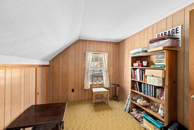 living area with carpet floors, vaulted ceiling, and wood walls