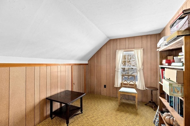 interior space with lofted ceiling, light colored carpet, and wood walls