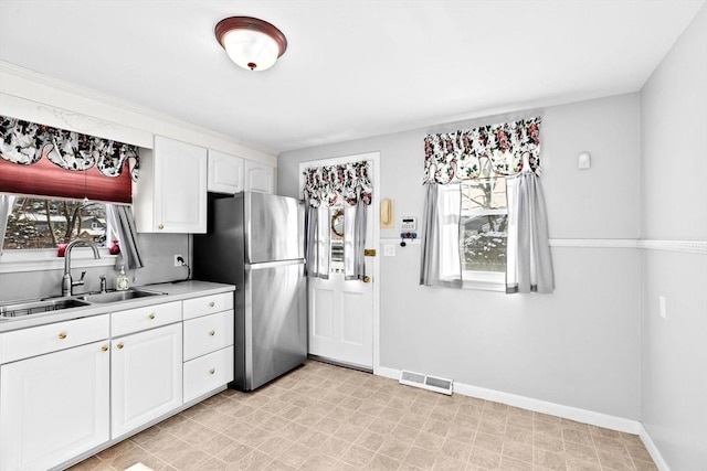 kitchen with stainless steel fridge, plenty of natural light, sink, and white cabinets