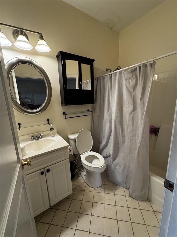 bathroom with toilet, shower / bath combo with shower curtain, vanity, and tile patterned floors