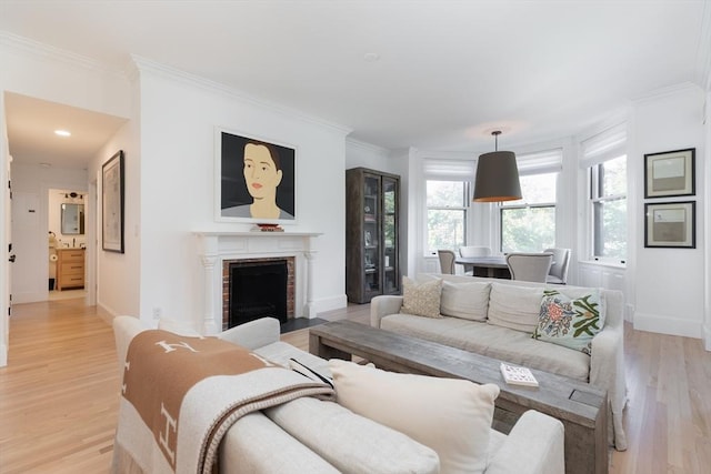 living room featuring a brick fireplace, light hardwood / wood-style flooring, and crown molding