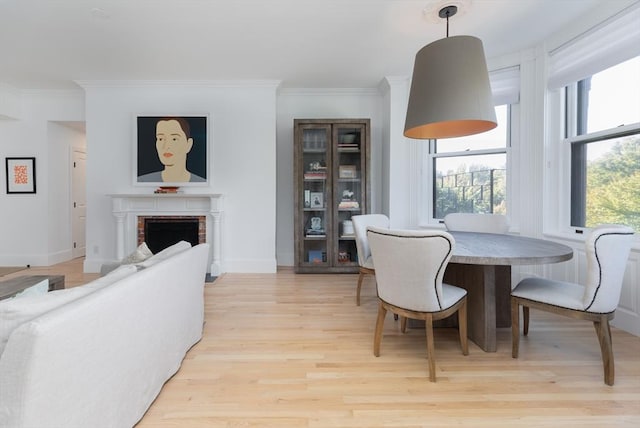 dining space with a fireplace, light hardwood / wood-style floors, and crown molding