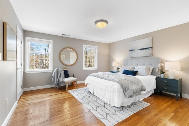 bedroom with light wood-style floors, baseboards, multiple windows, and visible vents