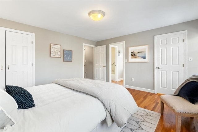 bedroom featuring light wood-type flooring, baseboards, and ensuite bathroom