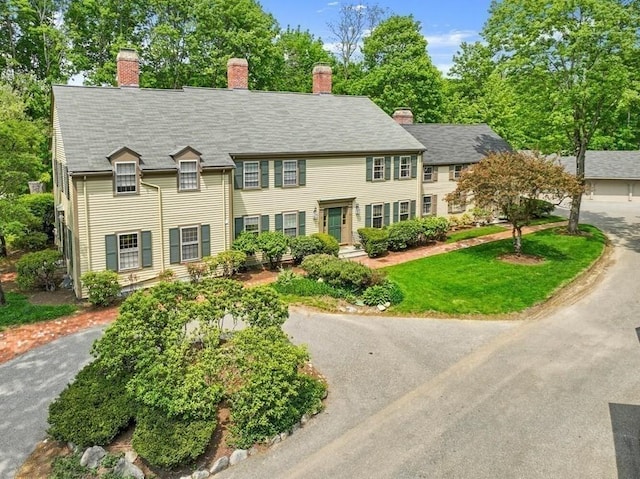 colonial home with a chimney and a front yard