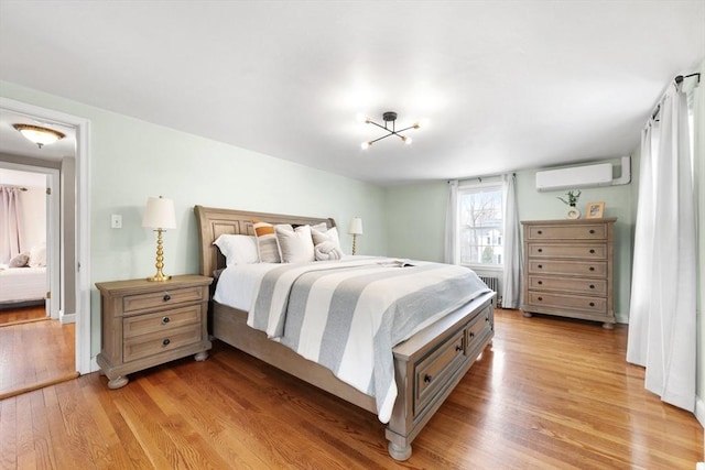 bedroom featuring light wood-style floors, radiator heating unit, and a wall mounted AC