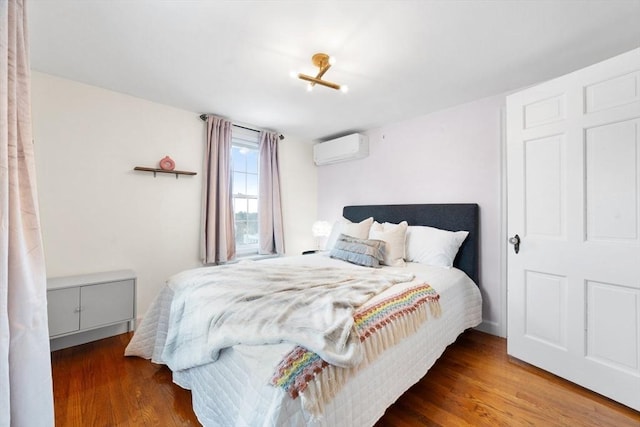 bedroom featuring wood finished floors and a wall mounted air conditioner