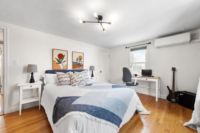 bedroom featuring a wall unit AC, light wood-style flooring, and baseboards