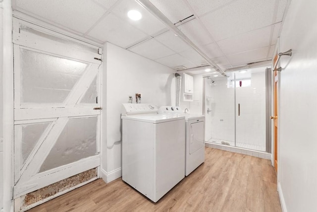 laundry area featuring washer and dryer, laundry area, baseboards, and light wood finished floors