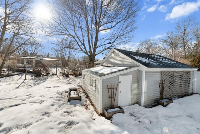 snow covered structure with an outbuilding