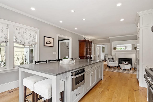 59 Elm St, Concord, MA 01742 - kitchen with stainless steel appliances, a breakfast bar area, a center island with sink, white cabinetry, and a fireplace