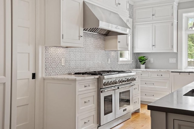 59 Elm St, Concord, MA 01742 - kitchen with range with two ovens, wall chimney range hood, and white cabinetry
