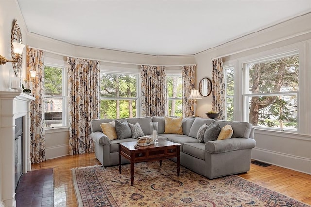 59 Elm St, Concord, MA 01742 - living area with healthy amount of natural light, wood-type flooring, a glass covered fireplace, and crown molding