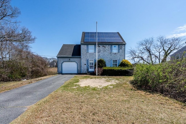 view of front of house with a garage, asphalt driveway, solar panels, and a front yard