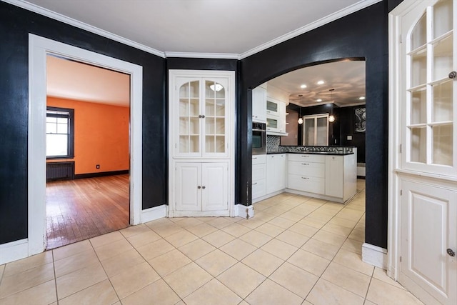 kitchen featuring white cabinetry, radiator, stainless steel oven, and light tile patterned flooring