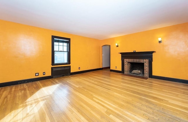 unfurnished living room with radiator, a fireplace, and light hardwood / wood-style floors