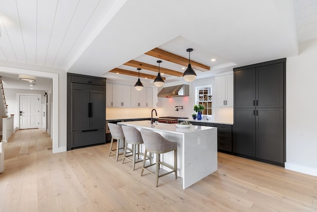 2 Candle House Ln, Nantucket, MA 02564 - kitchen featuring paneled fridge, a kitchen breakfast bar, light wood-type flooring, wall chimney range hood, and beam ceiling
