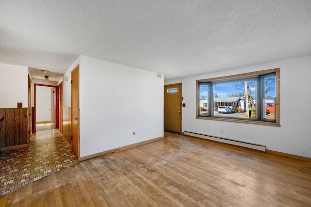 empty room featuring a textured ceiling, light wood-type flooring, and a baseboard radiator