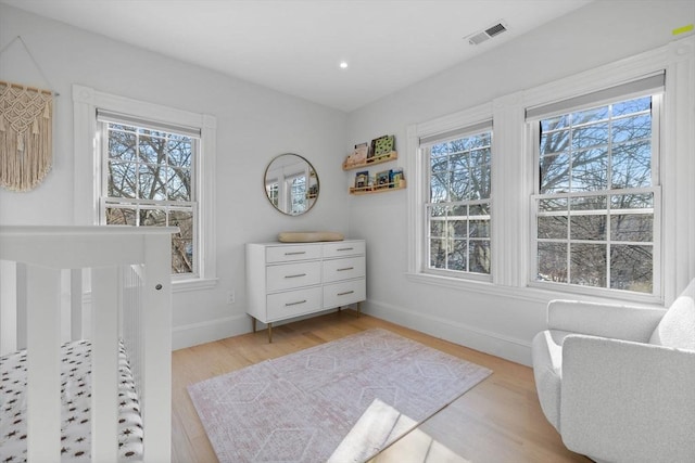 bedroom with light wood finished floors, baseboards, multiple windows, and visible vents