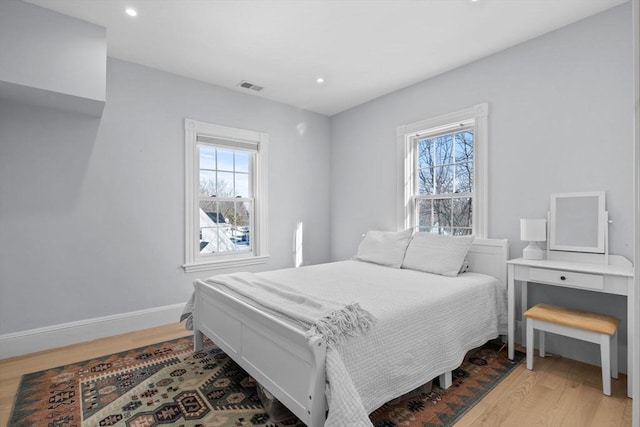 bedroom featuring light wood-type flooring, multiple windows, visible vents, and baseboards