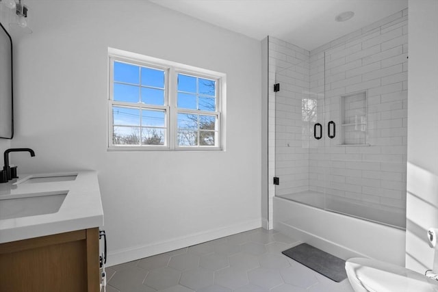 bathroom featuring shower / bath combination with glass door, double vanity, toilet, a sink, and baseboards