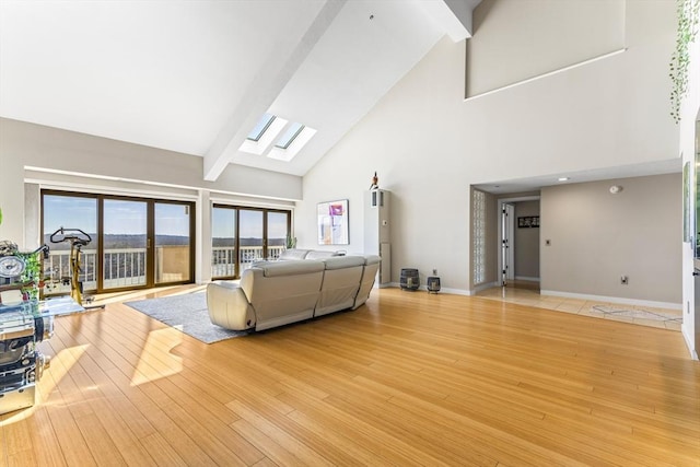 living area with wood finished floors, baseboards, high vaulted ceiling, a skylight, and beamed ceiling